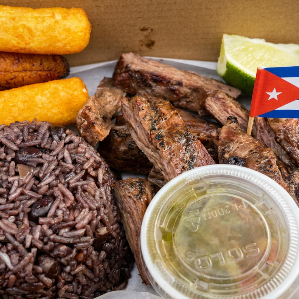 Cuban-style platter with grilled steak, black rice, fried plantains, lime, dipping sauce, and a Cuban flag.