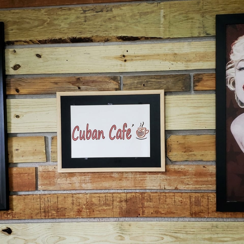 Rustic wooden wall displays framed Betty Boop and Marilyn Monroe portraits flanking a Cuban Cafe sign.